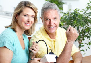 caregiver and elderly man testing blood pressure