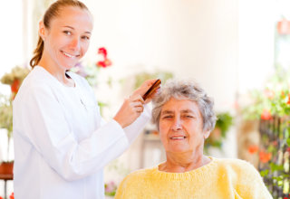 caregiver combing hair of old woman