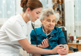 caregiver checking blood pressure of old woman