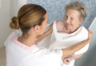 caregiver assisting old woman in taking a bath